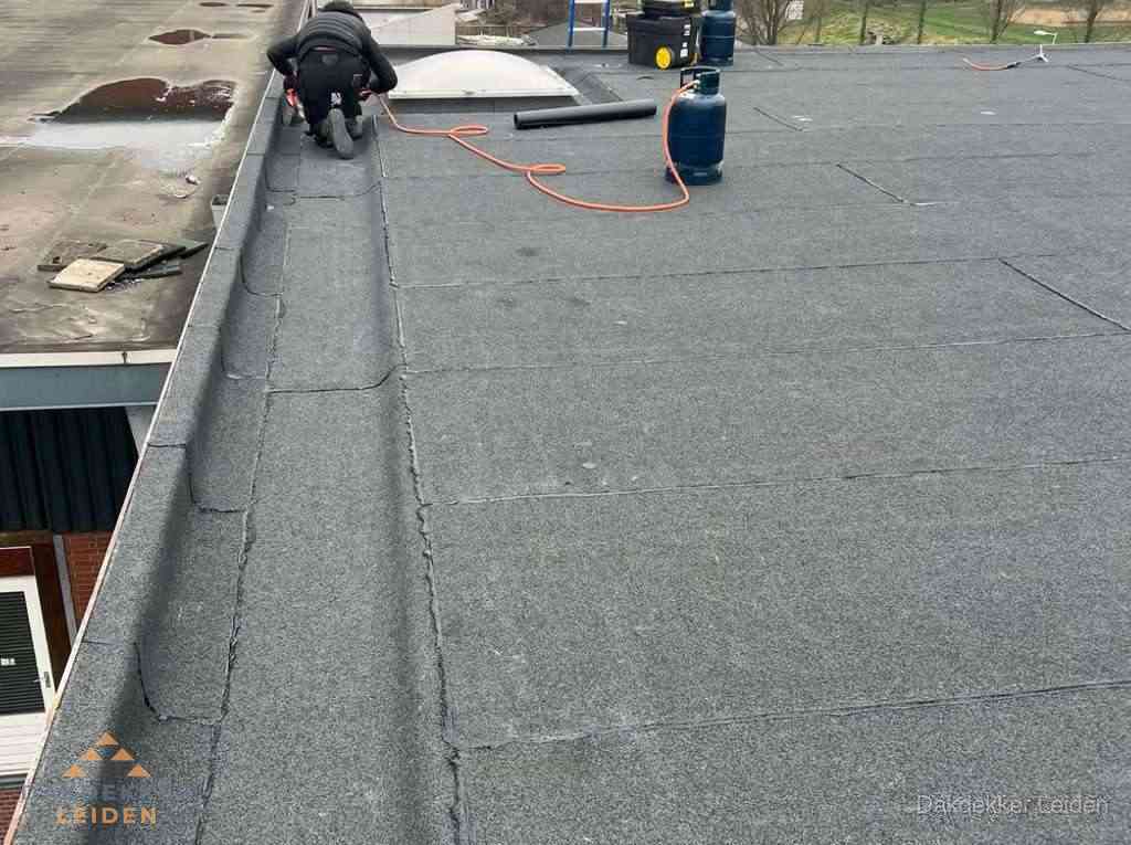 Dakdekker repareert bitumen dakbedekking op groot plat dak in Leiden Dakdekker repareert bitumen dakbedekking op groot plat dak in Leiden